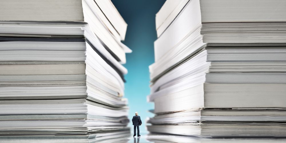 Uomo che cammina in mezzo a delle pile di documenti