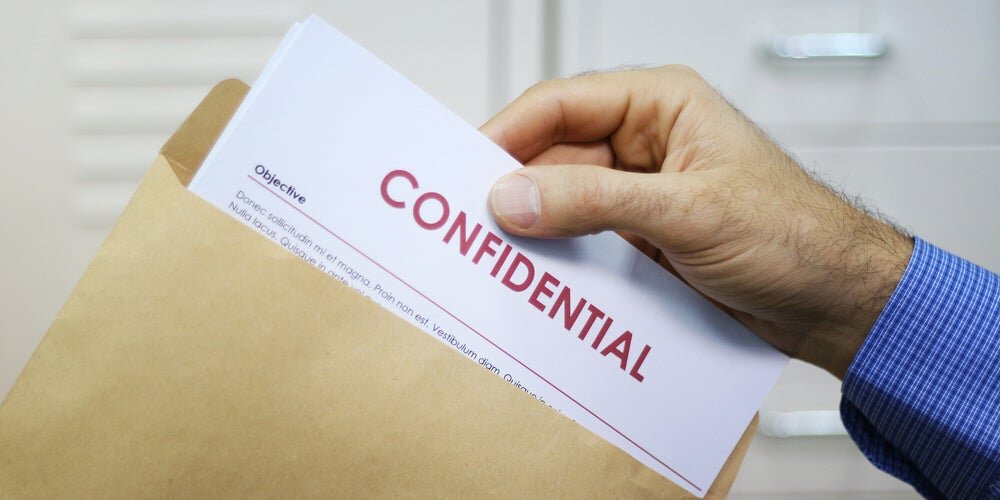 Mano che apre una busta ed estrae un foglio col titolo "Confidential"