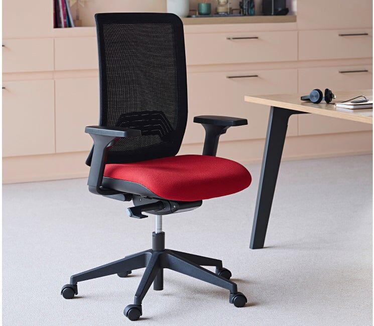 Chaise de bureau Imax dossier maille noir et assise rouge mécanisme synchrone auto régulé dans un décor de bureau.