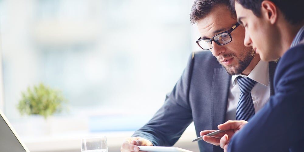 Manager con gli occhiali che legge un foglio insieme ad un dipendente