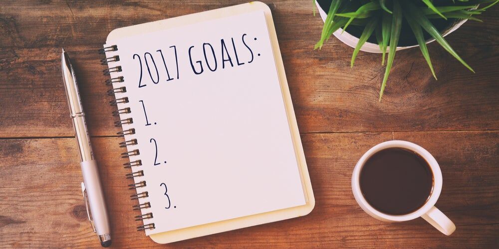 Taccuino con la scritta "2017 Goals", penna e tazza di caffè su una scrivania di legno