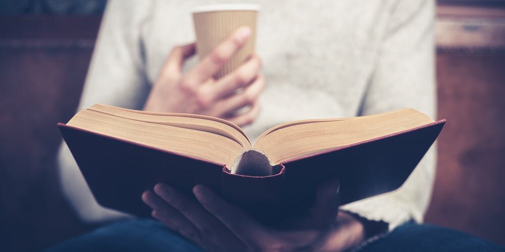 Uomo che legge un libro e beve del caffè